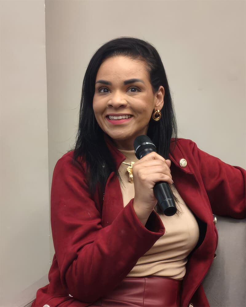 Cilene Danta falando ao microfone em um evento da Café em Código